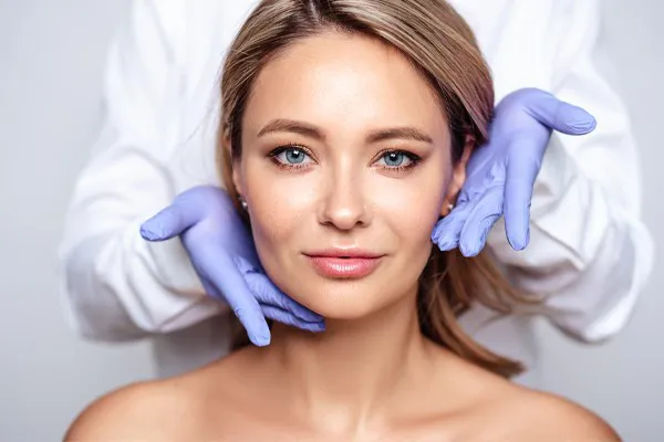 Close up of a woman's face with a doctor wearing rubber gloves standing behind her holding his hands around her face to show the amazing Botox Cosmetic treatment from Dr. Hadi Michael Rassael at Millennium Wellness in Bethesda-Chevy Chase.