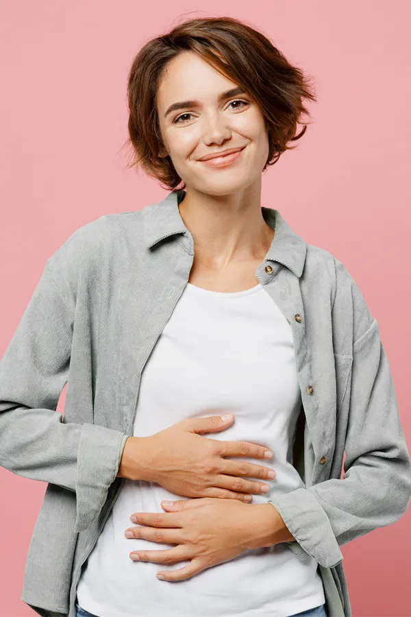 A woman with smaller breasts stands smiling. Get breast reduction treatment from Dr. Hadi Michael Rassael at Millennium Wellness in Bethesda-Chevy Chase.