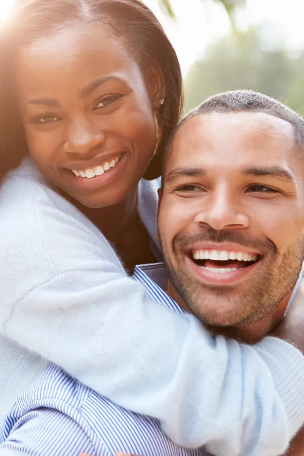 A woman riding on a man's back, both smiling due to help with erectile dysfunction from Dr. Hadi Michael Rassael at Millennium Wellness in Bethesda-Chevy Chase.