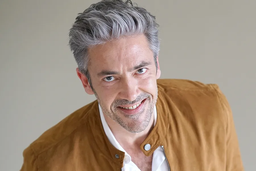 A middle-aged man with thick, full hair. Schedule FUE (Follicular Unit Extraction) transplant treatment from Dr. Hadi Michael Rassael at Millennium Wellness in Bethesda-Chevy Chase.