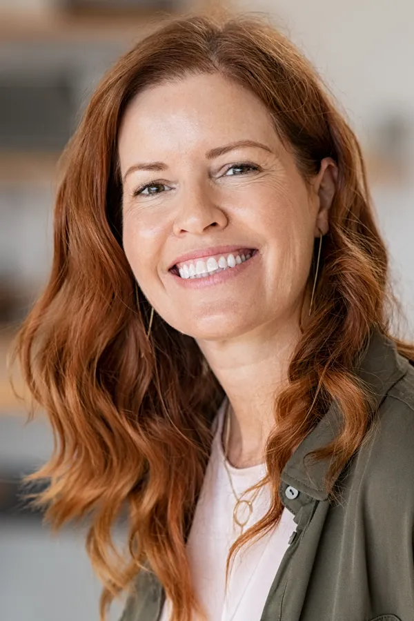 A beautiful woman with long, full red hair. Get FUE (Follicular Unit Extraction) transplant treatment from Dr. Hadi Michael Rassael at Millennium Wellness in Bethesda-Chevy Chase.