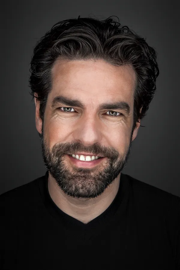 A smiling dark-haired man with a full, even beard. Get facial hair transplant treatment from Dr. Hadi Michael Rassael at Millennium Wellness in Bethesda-Chevy Chase.