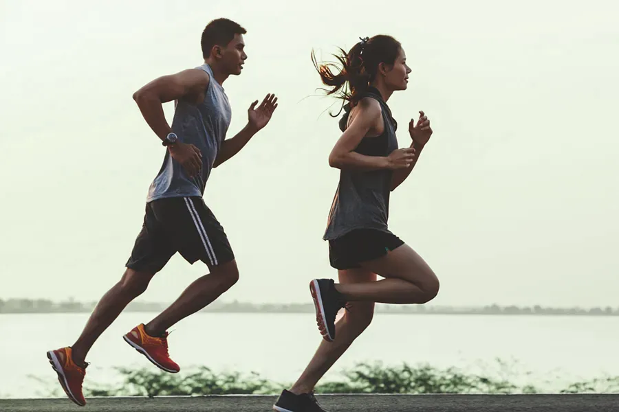 A couple in profile running along the water. Schedule GLP-1 Weight Loss Injections from Dr. Hadi Michael Rassael at Millennium Wellness in Bethesda-Chevy Chase.