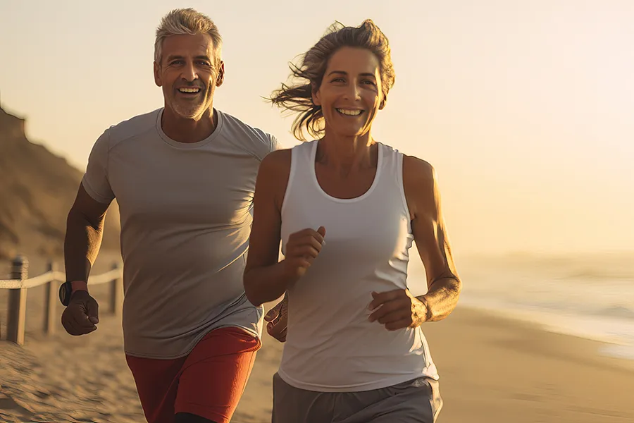 A mature couple happily going for a run on the beach. Schedule lipo light treatment from Dr. Hadi Michael Rassael at Millennium Wellness in Bethesda-Chevy Chase.