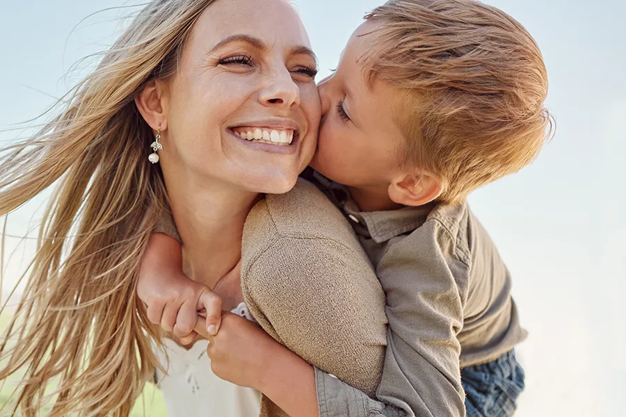 A beautiful mother plays with her son outside. Schedule a Mommy Makeover from Dr. Hadi Michael Rassael at Millennium Wellness in Bethesda-Chevy Chase.