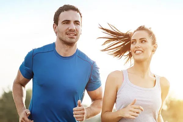 A couple happily jogging in the sunlight after receiving effective weight loss resistance care from Dr. Hadi Michael Rassael at Millennium Wellness in Bethesda-Chevy Chase.