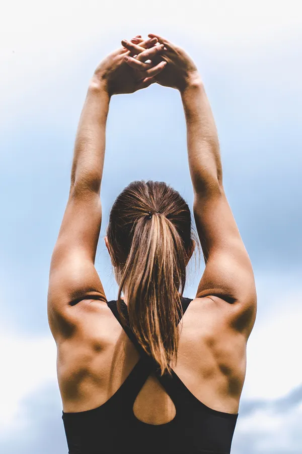 A fit, toned woman stretches her arms in the air. Get Zerona body sculpting treatment from Dr. Hadi Michael Rassael at Millennium Wellness in Bethesda-Chevy Chase.